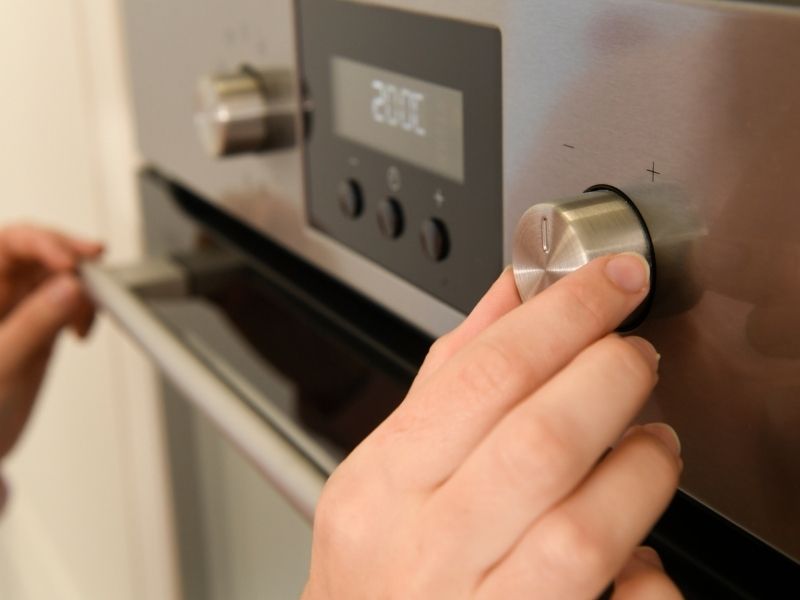 tangan sedang mengatur suhu oven